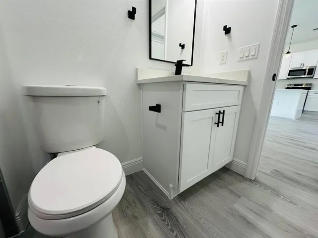a bathroom with a toilet a sink and wooden floor