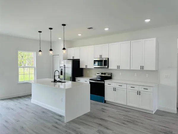 a kitchen with stainless steel appliances a stove top oven a sink a refrigerator a center island and cabinets