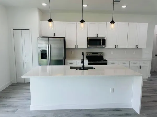 a kitchen with stainless steel appliances a stove a refrigerator a sink and white cabinets