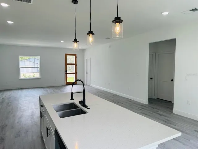 a kitchen with stainless steel appliances a kitchen island a stove a sink a window and wooden floor