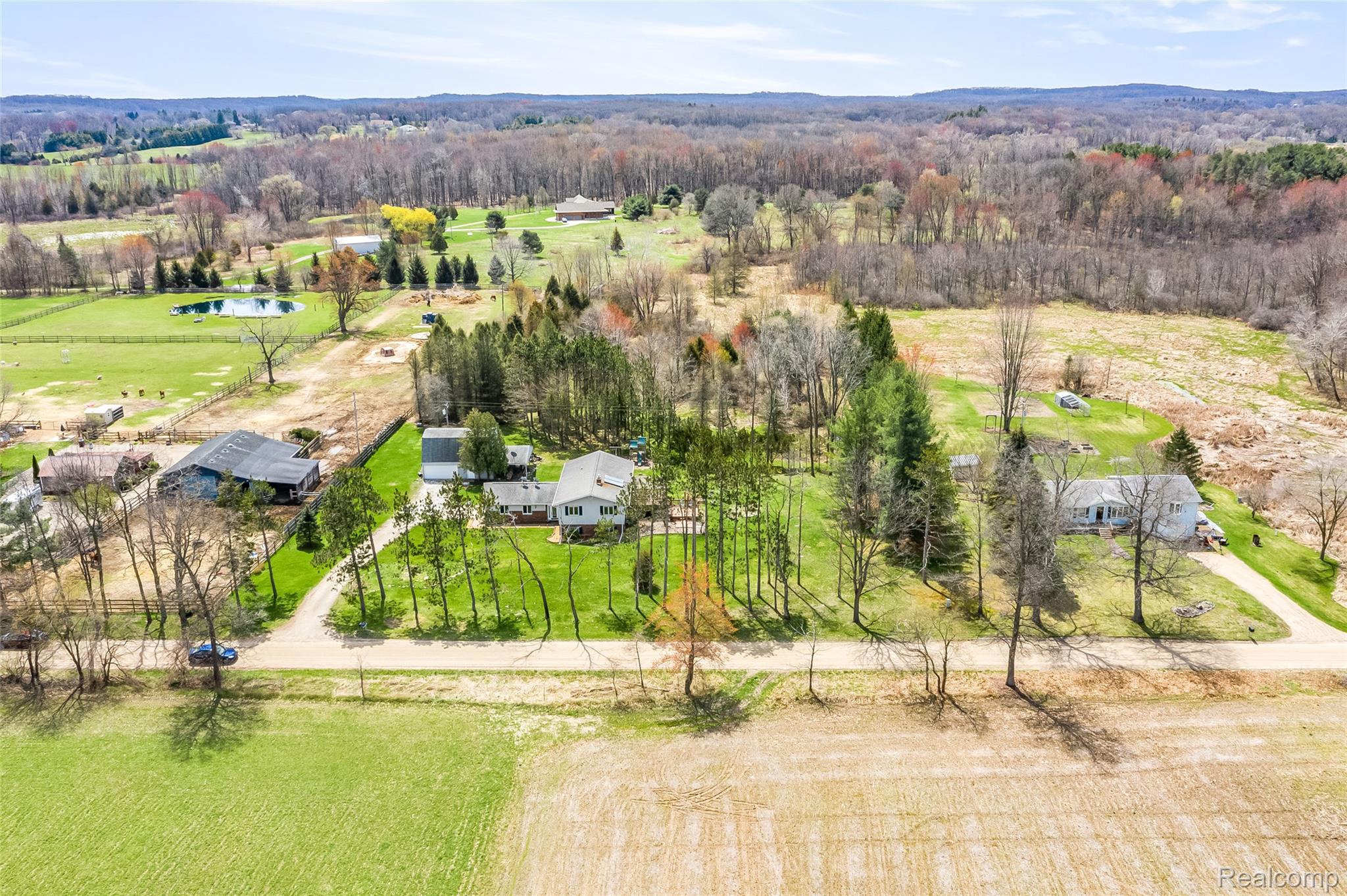 15395 Osius Road Chelsea, MI 48118 - Photo 51 of 55 Aerial perspective showcasing multiple residential structures, expansive green lawns, mature trees, and a distant pond