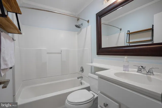a bathroom with a granite countertop bathtub shower sink vanity mirror and toilet
