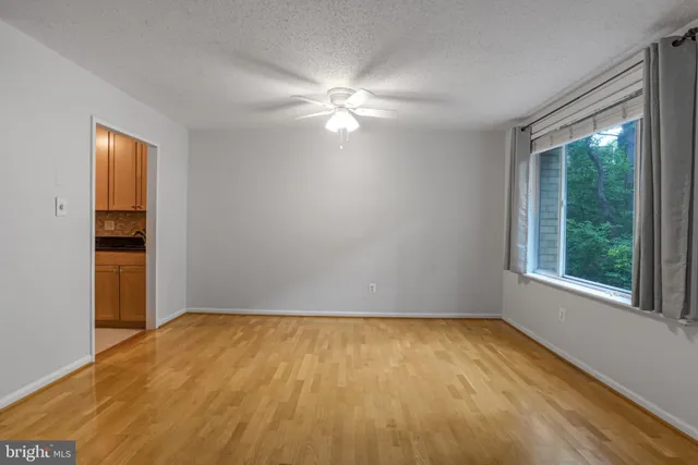 a view of empty room with wooden floor and fan