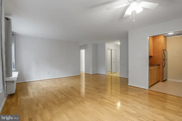 a view of an empty room with wooden floor and a window