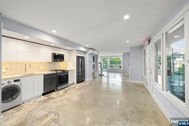 a view of a kitchen with a sink stove cabinets and empty room