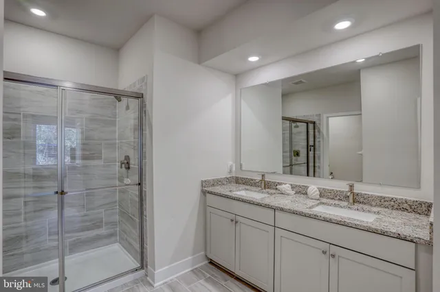 a bathroom with a granite countertop sink a mirror and shower