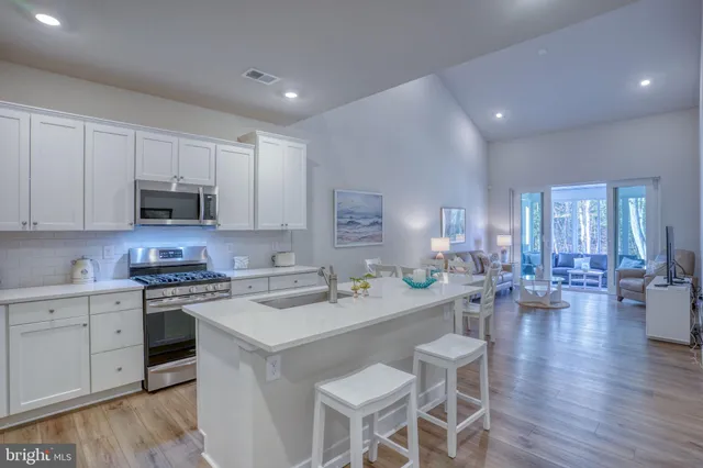 a kitchen with kitchen island granite countertop a sink a stove a oven a counter space and cabinets