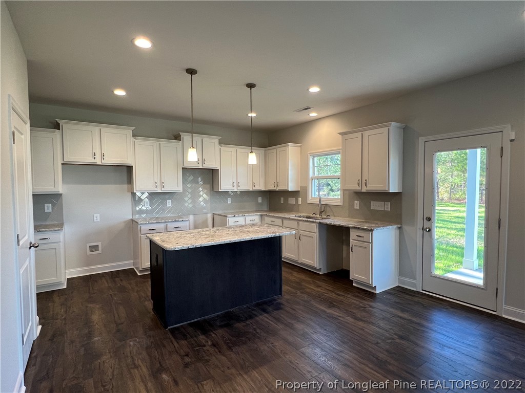 7850 Rufus Johnson Road Fayetteville, NC 28306 - Photo 4 of 11 a kitchen with kitchen island granite countertop a sink cabinets and wooden floor
