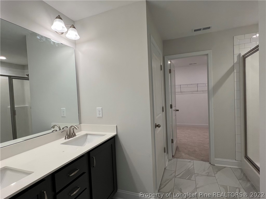 7850 Rufus Johnson Road Fayetteville, NC 28306 - Photo 9 of 11 a bathroom with a double vanity sink a shower and a mirror