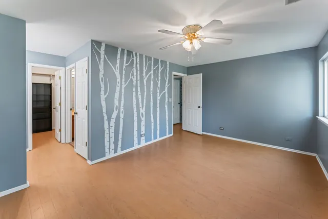 an empty room with chandelier fan and windows