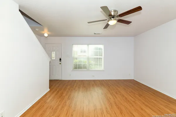 a view of an empty room with wooden floor and a window
