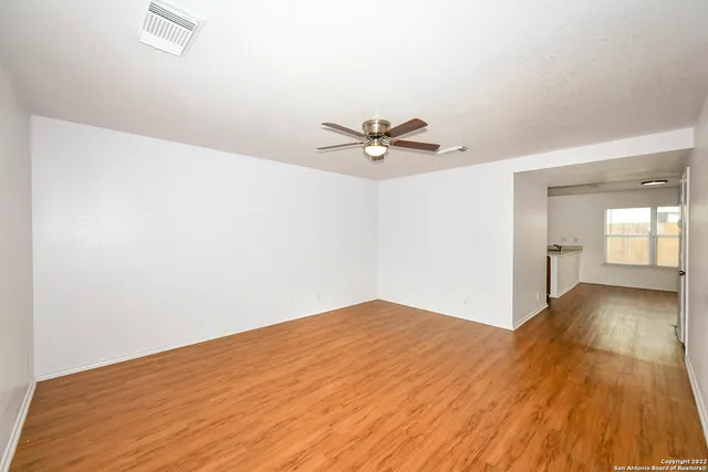 a view of a big room with wooden floor and a chandelier fan in a room