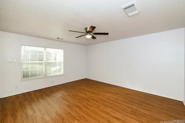 an empty room with wooden floor and windows