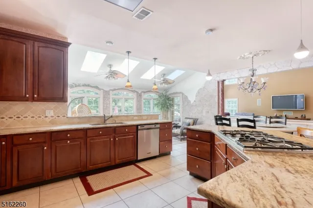 a kitchen with stainless steel appliances granite countertop a stove a sink dishwasher and a microwave oven with large wooden cabinets