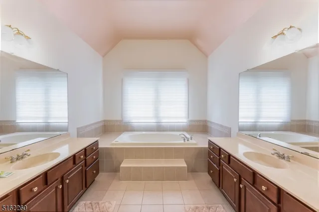 a spacious bathroom with a tub sink and a mirror