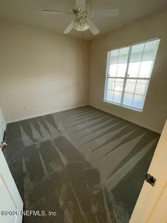 an empty room with windows and fan