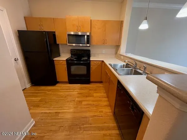 a kitchen with stainless steel appliances a refrigerator a sink and wooden cabinets