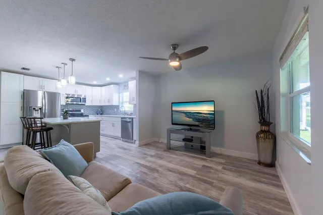 a living room with furniture and a flat screen tv with kitchen view