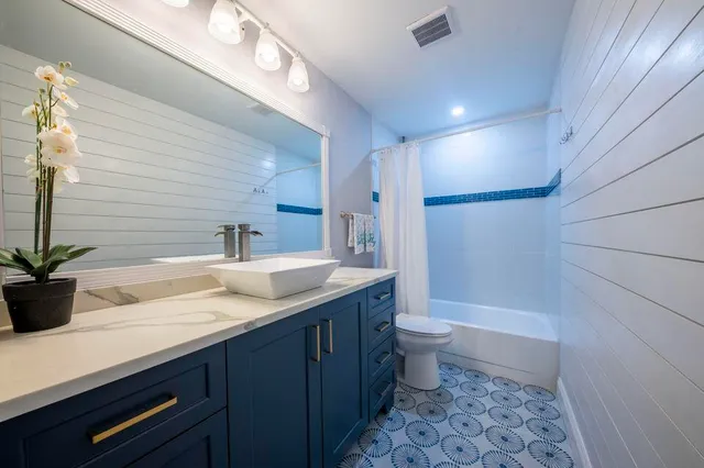 a bathroom with a granite countertop sink a toilet a large mirror and shower