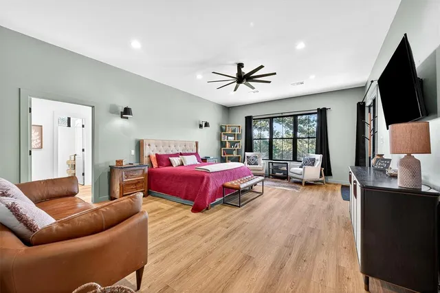 a spacious bedroom with a bed a couch and a flat tv screen on the dresser