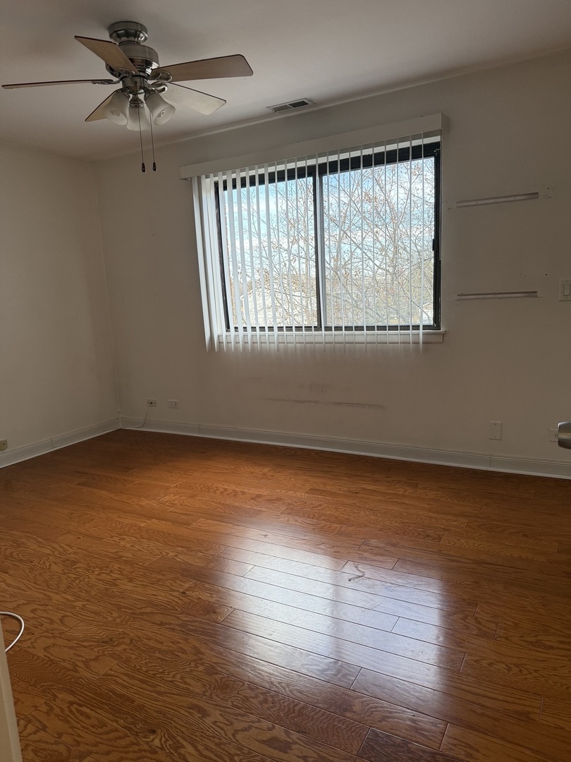 383 Wilmington Drive, Unit E Bartlett, IL 60103 - Photo 12 of 17 an empty room with wooden floor fan and windows