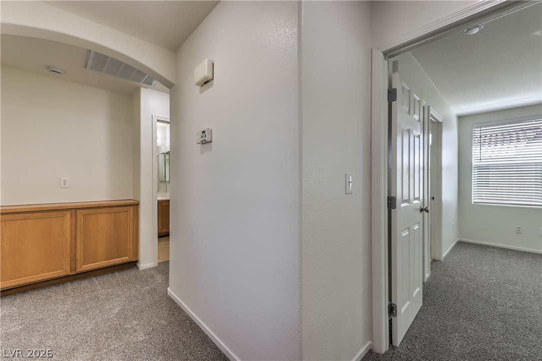 10939 Paradise Road Henderson, NV 89052 - Photo 21 of 36 A well-lit interior hallway offers plush carpeting and a glimpse into adjacent rooms.