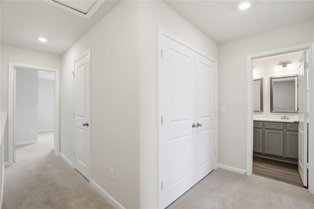305 Lilac Loop Greenwood, SC 29646 - Photo 11 of 25 A well-lit hallway with carpeted flooring provides access to a full bathroom.