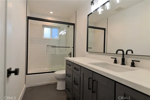 a bathroom with a granite countertop sink a toilet a mirror and shower