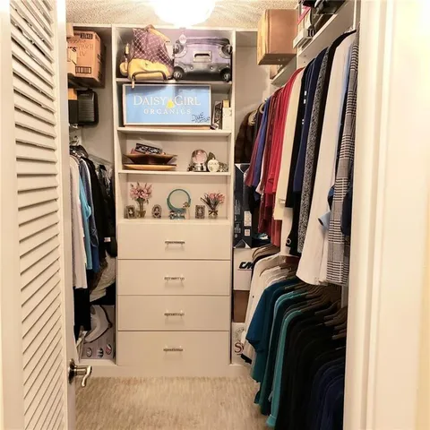 a view of walk in closet with clothes and shoes