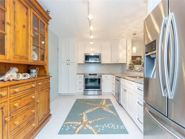 a kitchen with stainless steel appliances granite countertop a refrigerator and a stove top oven
