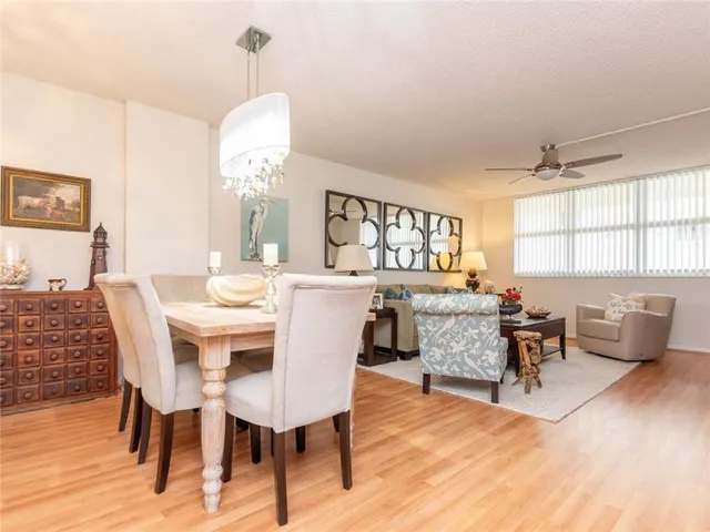 a dining room with wooden floor a chandelier a wooden table and chairs
