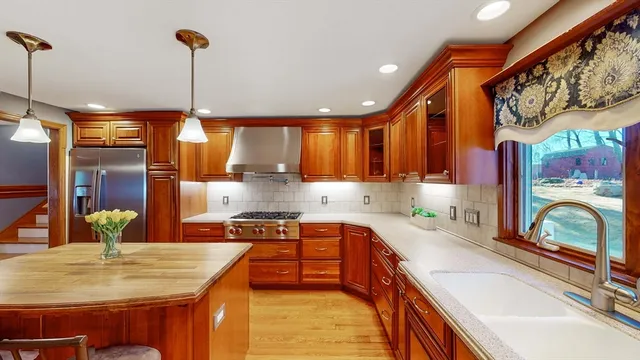 a kitchen with stainless steel appliances granite countertop a sink a stove and a wooden floors