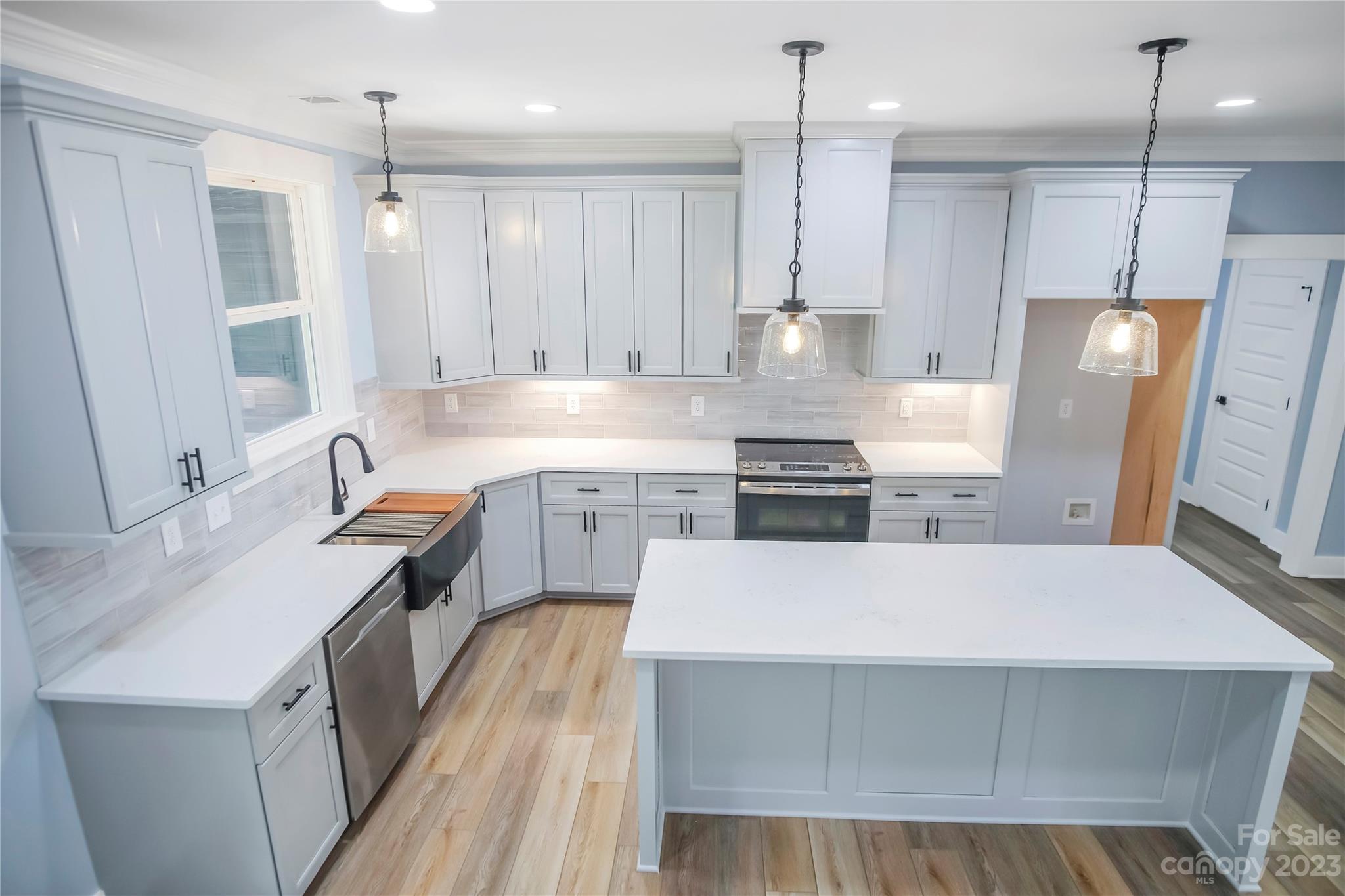 7550 Webbs Road Denver, NC 28037 - Photo 15 of 46 a large kitchen with stainless steel appliances a stove a sink dishwasher a refrigerator white cabinets and wooden floor