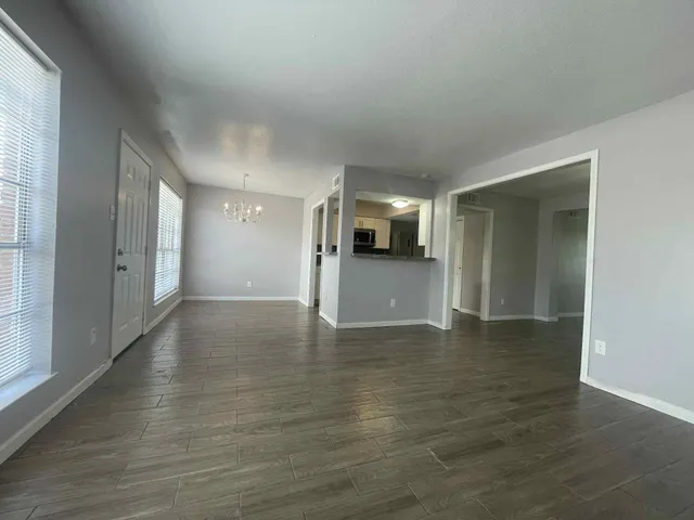 a view of a big room with wooden floor and a kitchen