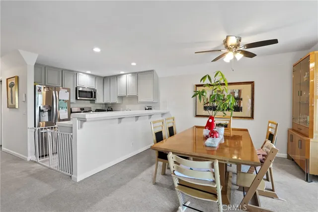 a living room with stainless steel appliances furniture a chandelier and a dining table