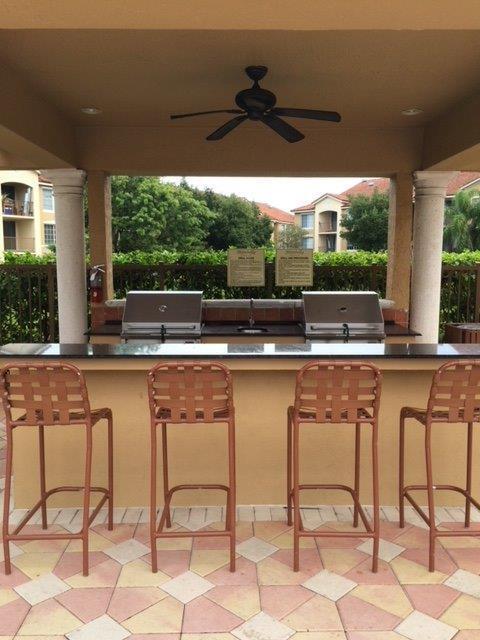 602 Villa Circle Boynton Beach, FL 33435 - Photo 25 of 27 a view of a patio with table and chairs under an umbrella with large trees