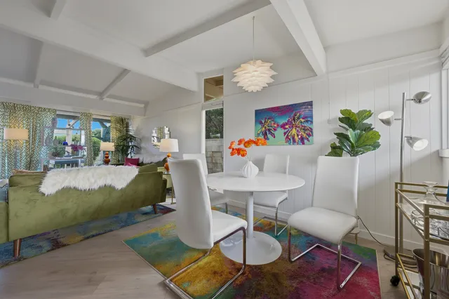 a living room with patio a dining table a chandelier and a dining table with wooden floor