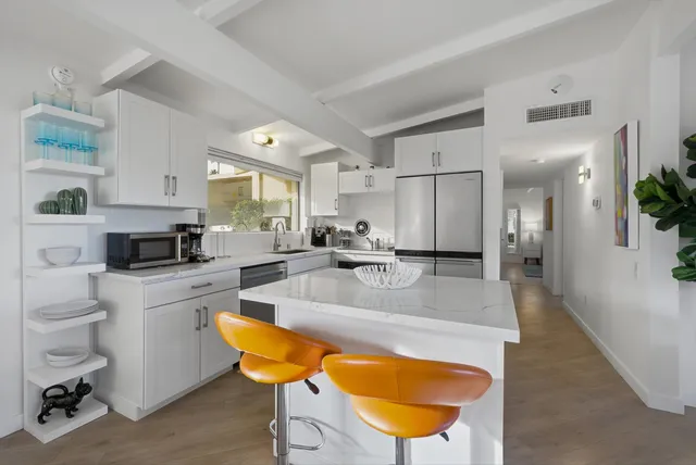 a large white kitchen with a refrigerator a stove a sink dishwasher and white cabinets with wooden floor