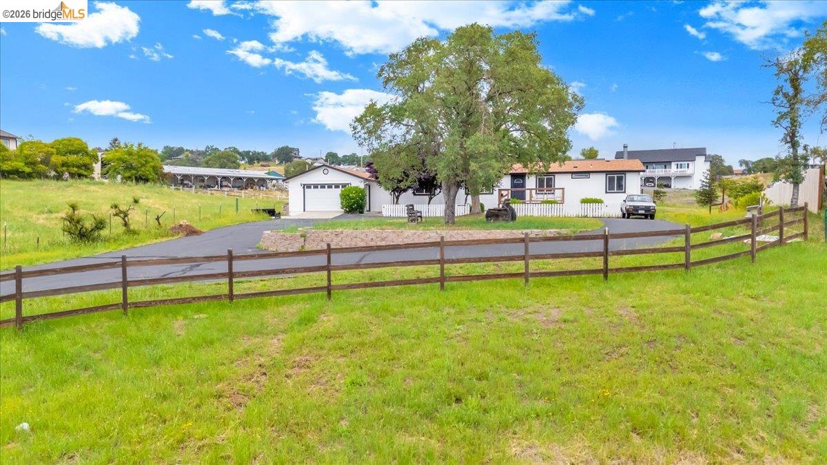 4419 Little John Road Copperopolis, CA 95228 - Photo 1 of 43 Spacious rural property featuring a white exterior residence, detached garage with roll-up door, paved driveway, and perimeter split-rail fencing