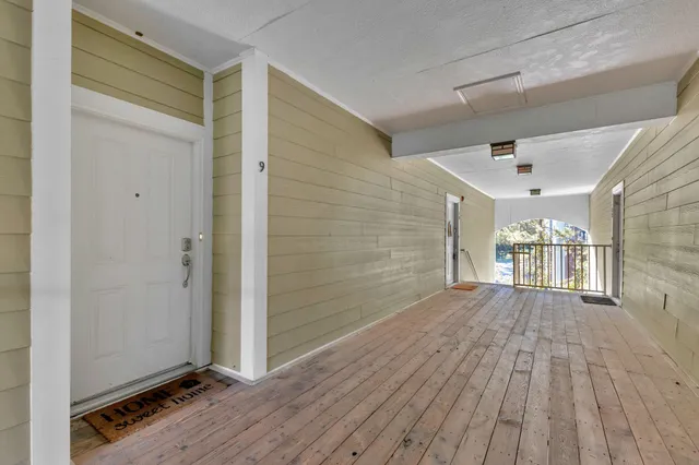 a view of a hallway with wooden floor and a bathroom