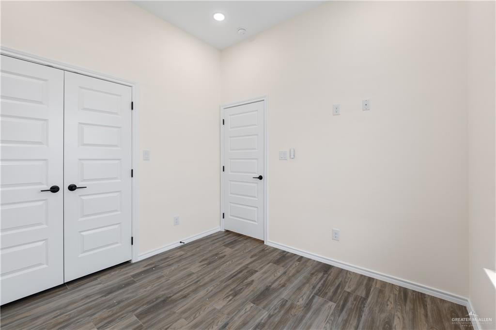 18054 Spruce Street Combes, TX 78552 - Photo 12 of 25 Room with vaulted ceiling, wood-finish flooring, white doors with matte black hardware, recessed lighting, and light-toned walls