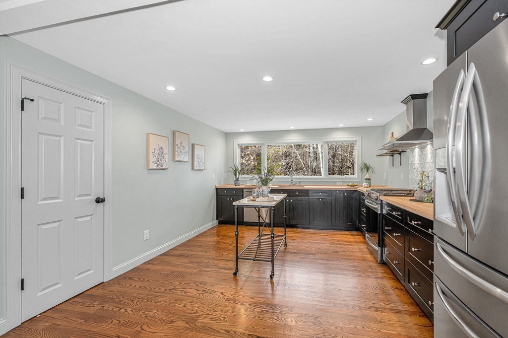 29 Washington Street Boxford, MA 01921 - Photo 11 of 39 a kitchen with stainless steel appliances granite countertop a refrigerator a stove top oven and a dining table with wooden floor