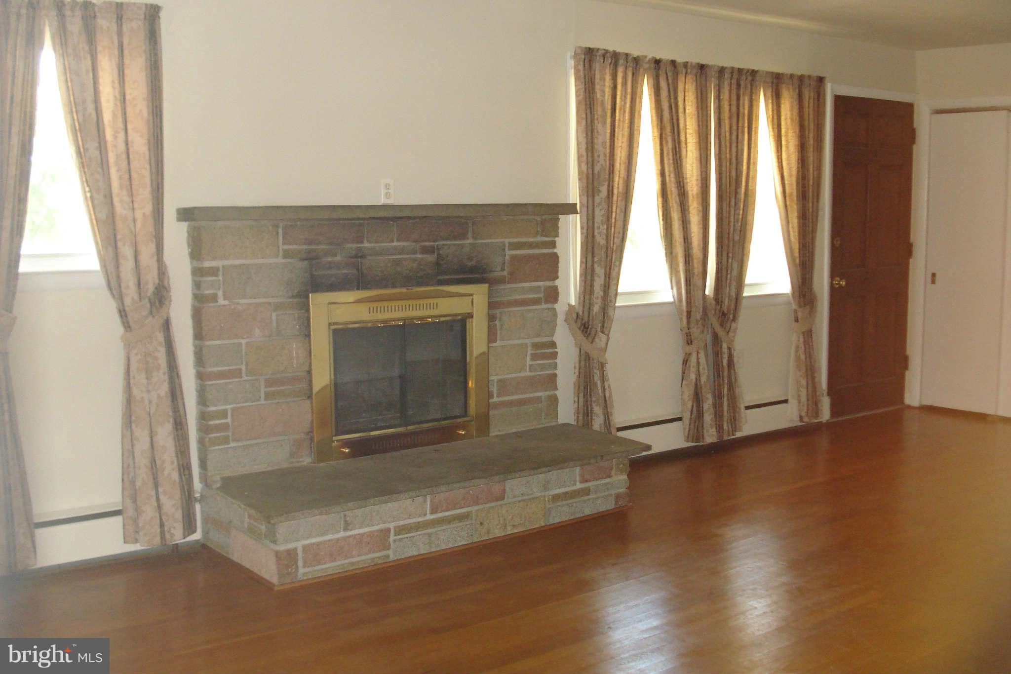 15725 Barnesville Road Boyds, MD 20841 - Photo 7 of 11 an empty room with wooden floor fireplace and windows