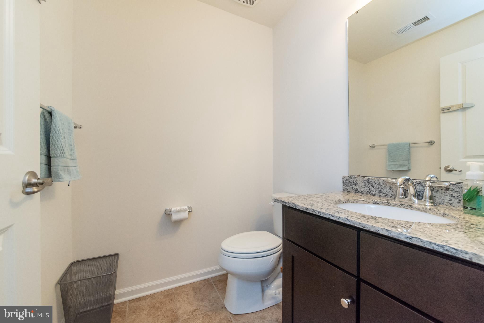 10426 Windlass Run Road Baltimore, MD 21220 - Photo 52 of 56 a bathroom with a granite countertop toilet a sink and a mirror