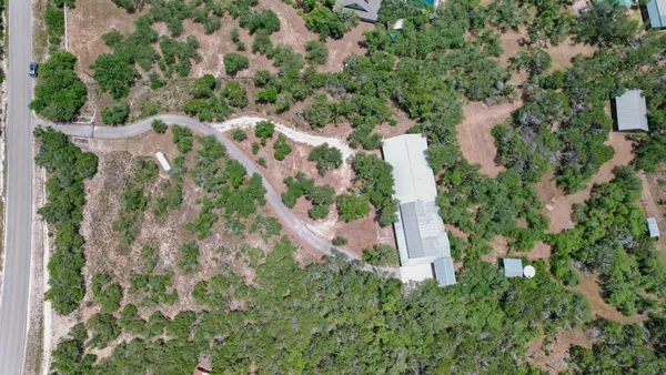 an aerial view of residential house with outdoor space and trees all around