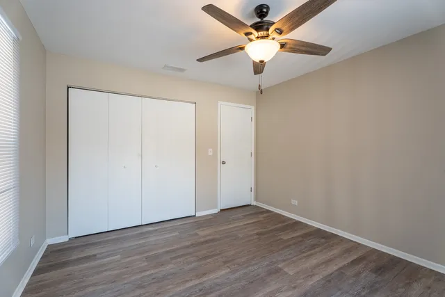 an empty room with wooden floor and fan