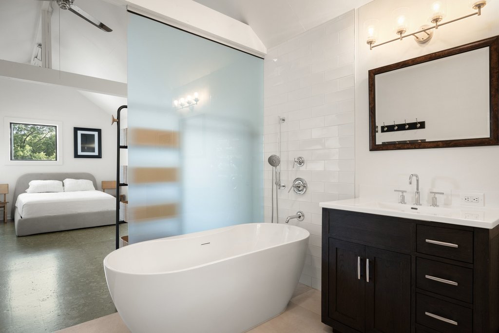 4707 Peace Pipe Path Austin, TX 78746 - Photo 37 of 40 a bathroom with a white tub a sink and wooden floor