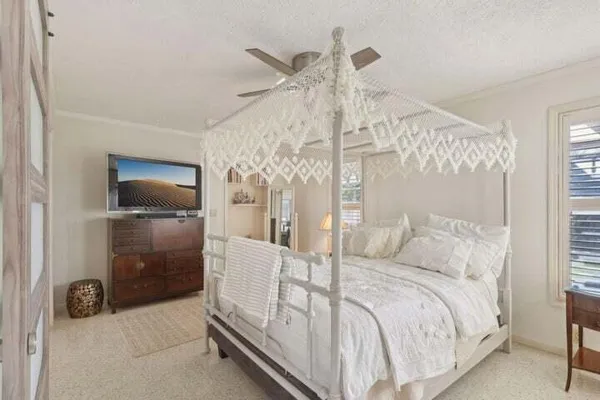 a bedroom with a bed and a flat tv screen on the dresser