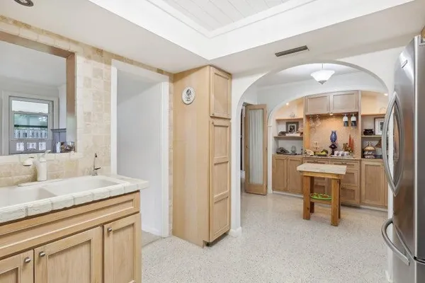 a living room with kitchen island a white cabinets and refrigerator