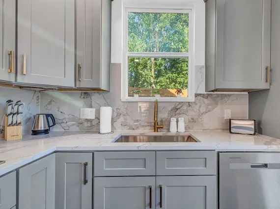a kitchen with granite countertop white cabinets and a window